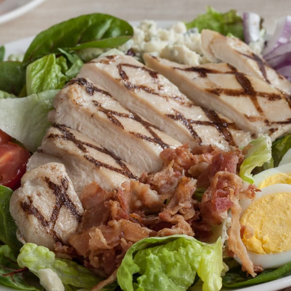 Grilled chicken salad with bacon, hard-boiled egg, tomatoes, red onion, and blue cheese crumbles.